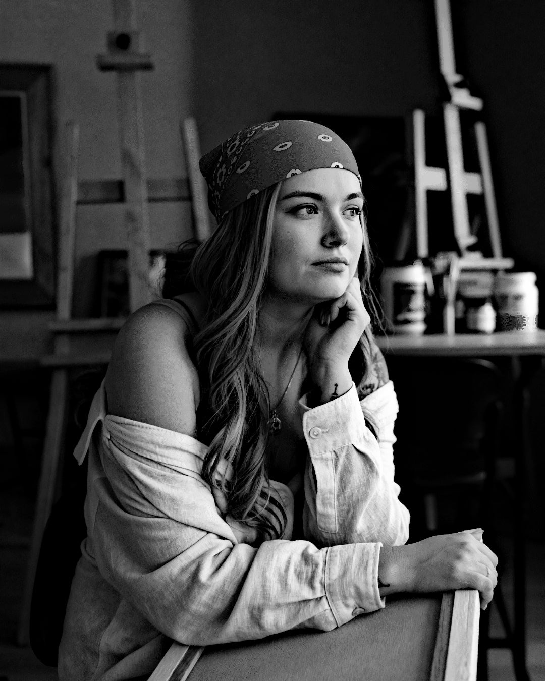 Black and white portrait of the artist in her studio with easels behind her